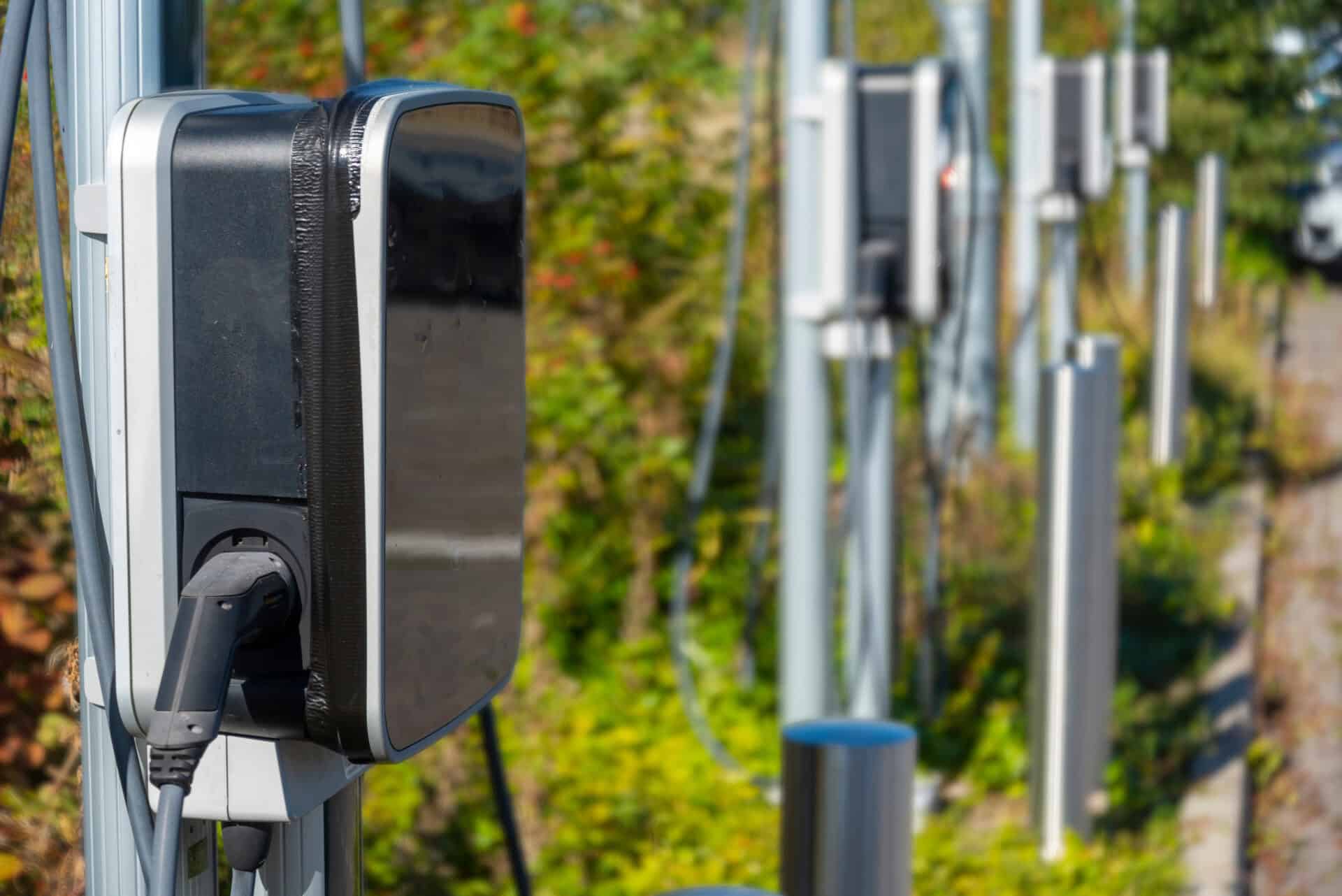 EV charge point,standing in a row, next to car parking spaces at a public electric vehicle charging location,situated within a railway station car park.